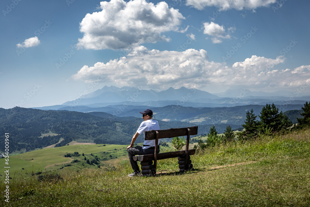 A man sitting on a wooden bench, watching a mountain landscape at Wysoki Wierch, Pieniny Mountains, Poland. A man sitting on a wooden bench, watching a mountain landscape at Wysoki Wierch, Pieniny Mountains, Poland.