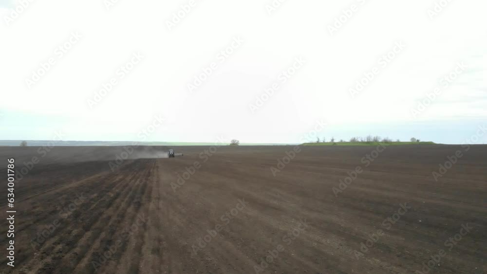 Blue tractor planting sunflower with yellow planter on the field in Ukraine Blue tractor planting sunflower with yellow planter on the field in Ukraine