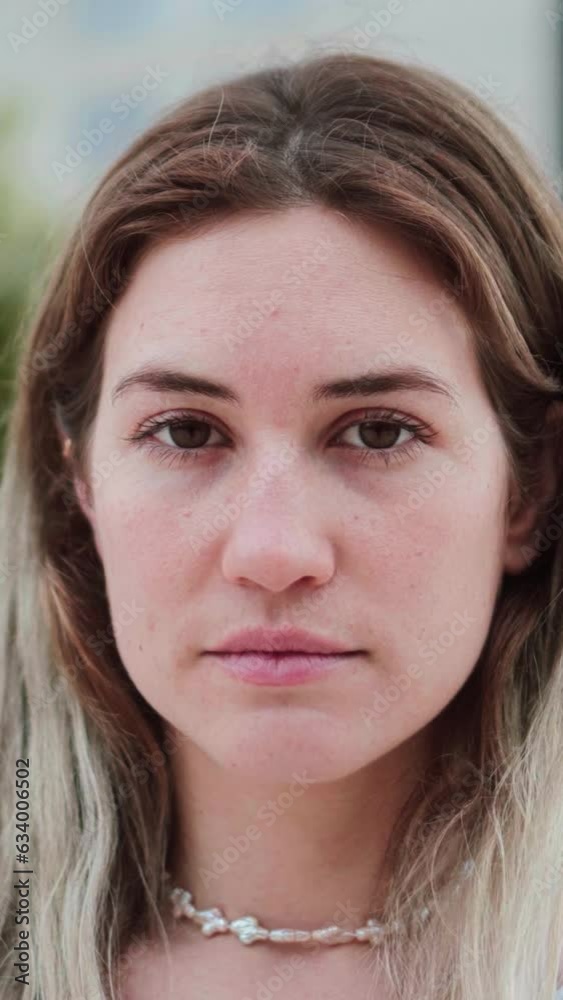 Vertical individual close up portrait of blonde caucasian young woman looking serious at camera. Pretty teenage girl staring front with sad attitude and pensive expression. High quality footage Vertical individual close up portrait of blonde caucasian young woman looking serious at camera. Pretty teenage girl staring front with sad attitude and pensive expression. High quality footage