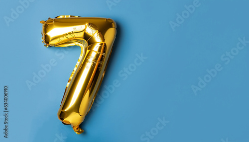 Banner with number 7 golden balloon with copy space. Seven years anniversary celebration concept on a blue background. photo