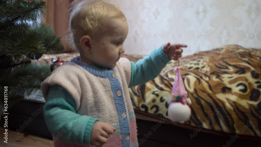 a baby is playing with a snowman toy,happy child dancing near christmas tree at home a baby is playing with a snowman toy,happy child dancing near christmas tree at home