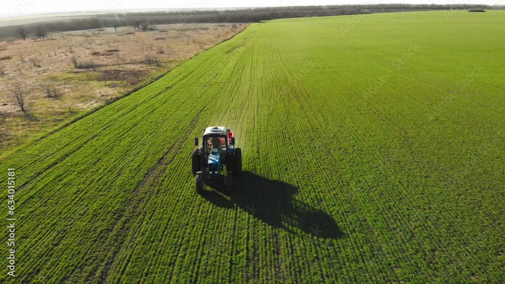 Farmer with agricultural machinery fertilizing agricultural field in spring time. Tractor spreads organic fertilizers on fertile soil to increase productivity. Farmer with a farm machine on farmland. Farmer with agricultural machinery fertilizing agricultural field in spring time. Tractor spreads organic fertilizers on fertile soil to increase productivity. Farmer with a farm machine on farmland.