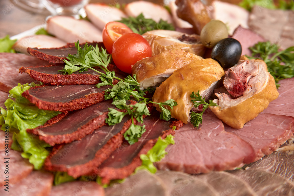 Part of plate with cold cuts with choice - salami, pieces of sliced ham, sausage, chicken, qazi horse meat, tomatoes on salad, close-up, shallow depth of field Part of plate with cold cuts with choice - salami, pieces of sliced ham, sausage, chicken, qazi horse meat, tomatoes on salad, close-up, shallow depth of field