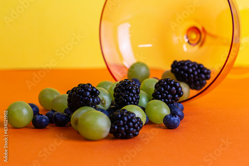 Blackberries and Grapes in a Glass Bowl on a yellow and orange background (ID: 634021902)