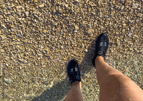 Feet in aquashoes in the water. Safety footwear for swimming. photo