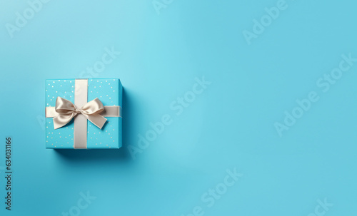 Blue gift box with satin ribbon on blue background. Top view of birthday gift with space for text