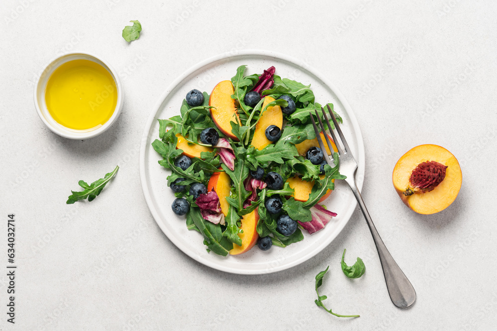 Peach arugula blueberry salad in plate on white background. Delicious fruit salad Peach arugula blueberry salad in plate on white background. Delicious fruit salad