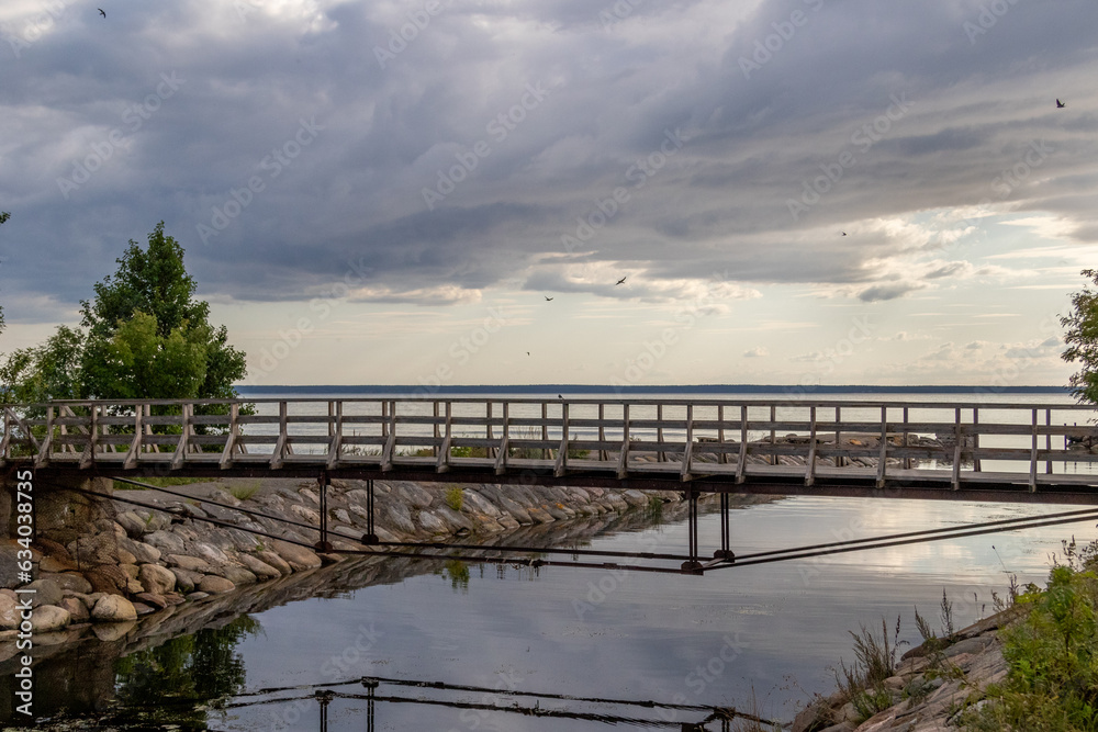 abandoned bridge over a river, image shows a bridge in a abandoned soviet facility on the coast of Parispea, lahemaa national park , Estonia with a calm sea and sunset. August 2023