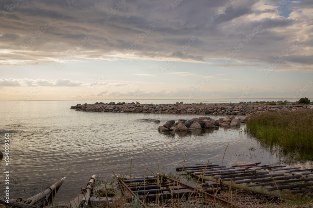 Sunset view from parispea beach in Lahemaa national park, Estonia. Image shows sunset with partial clouds and a calm sea washing over the rocky water break and beach. August 2023 Sunset view from parispea beach in Lahemaa national park, Estonia. Image shows sunset with partial clouds and a calm sea washing over the rocky water break and beach. August 2023