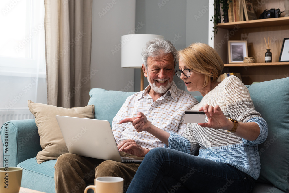 Senior couple at home sitting on sofa and shopping online on laptop. Senior husband and smiling wife paying bills online. Joyful middle aged couple doing online payment on digital tablet, copy space. Senior couple at home sitting on sofa and shopping online on laptop. Senior husband and smiling wife paying bills online. Joyful middle aged couple doing online payment on digital tablet, copy space.