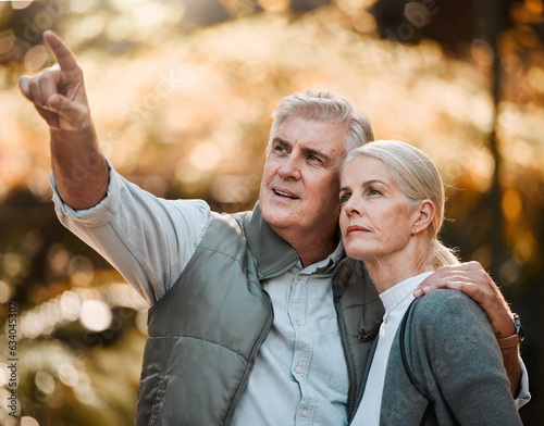 Senior couple, outdoor hiking and pointing with thinking, view or direction in nature, sunshine or adventure. Elderly man, woman and together with vision, walk or check environment on holiday in park