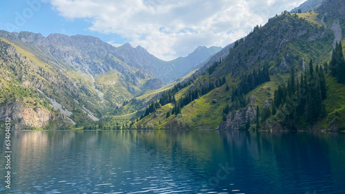 Amazing view of the green wooded hills, mountains and rocks at the beautiful lake Sary Chelek. The State Biosphere Reserve is a specially protected natural territory of Kyrgyzstan.
