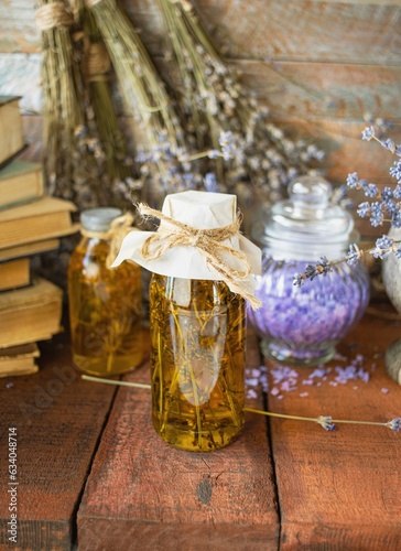 Vintage books, dried lavender flowers and bottles of essential oil on wooden background.