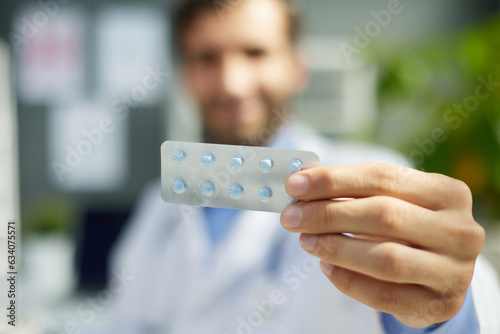Close-up portrait of nice attractive doc apothecary holding in hand bottle of organic pills