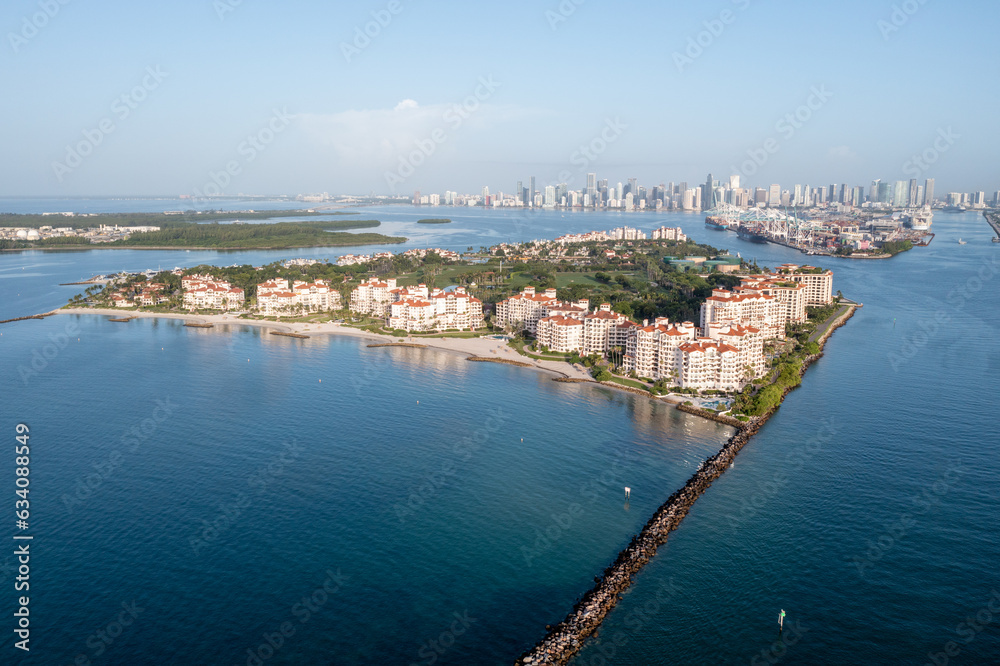 Aerial view of Fisher Island at sunrise with City of Miami skyline and Port Miami in background on calm clear summer morning..