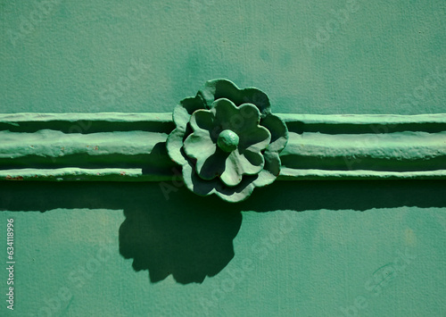 Fényképezés painted green metal plate door with rose shaped wrought iron ornament and horizontal bar trim