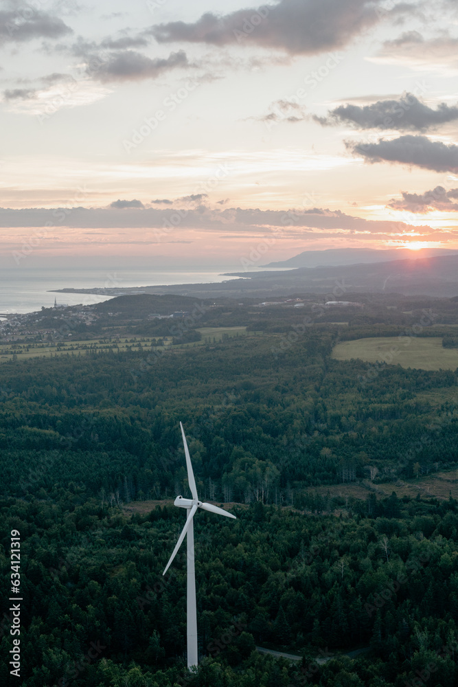 vue en hauteur d'une éolienne dans une forêt avec le fleuve en arrière plan aux premières lueurs du matin vue en hauteur d'une éolienne dans une forêt avec le fleuve en arrière plan aux premières lueurs du matin