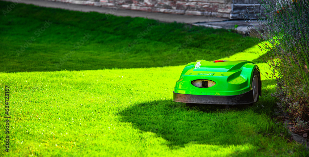 New modern robotic lawnmower on the grass. Gardener equipment...
