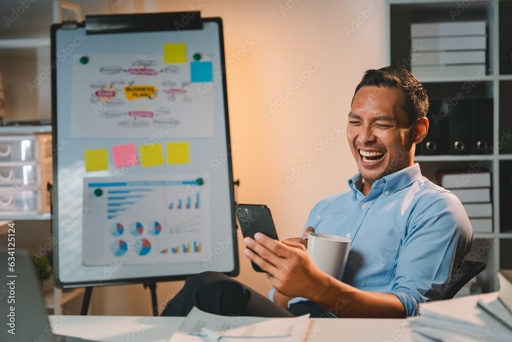 young man working at night Work comfortably on your smartphone. Social media chat at the office young man working at night Work comfortably on your smartphone. Social media chat at the office
