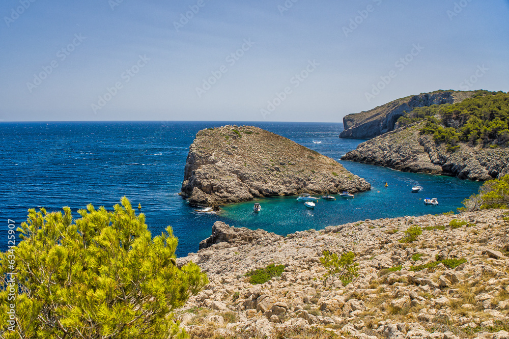 view of a small bay on the costa brava where motorboats are anchored under a sunny blue sky