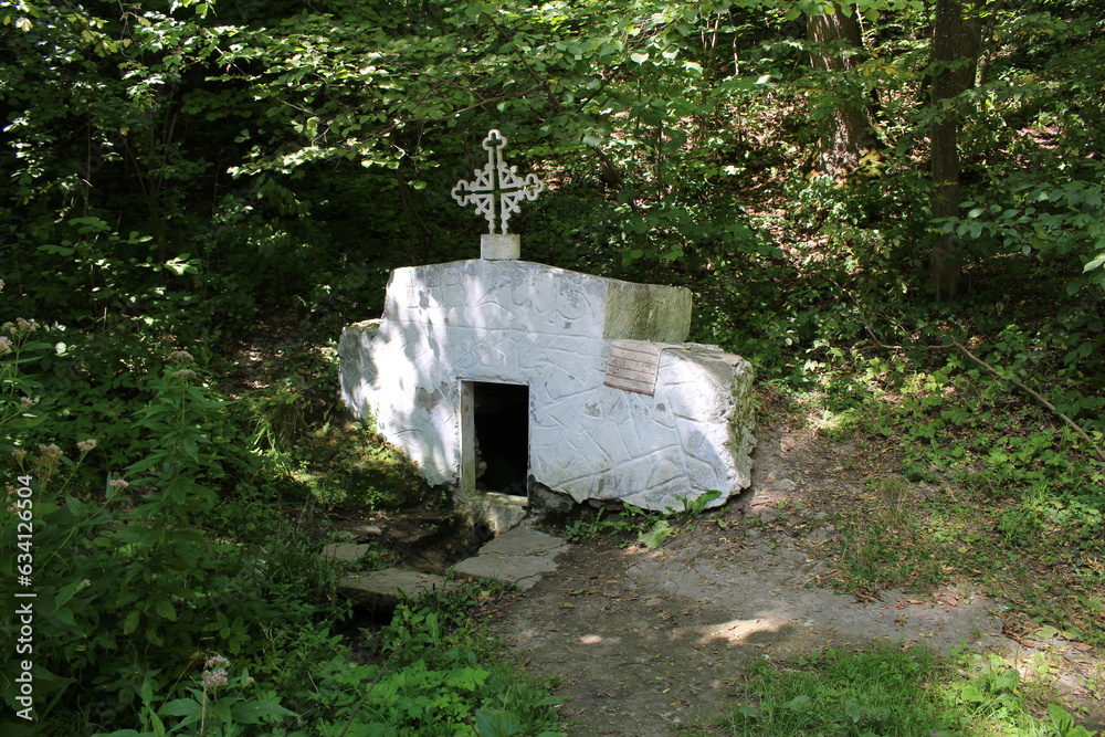A small white stone structure with a cross on top A small white stone structure with a cross on top
