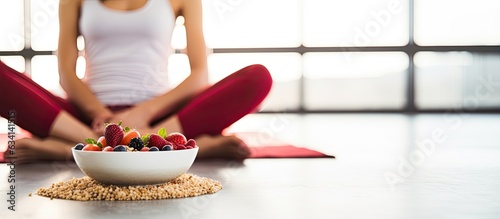 Fit woman enjoying healthy food after fitness exercise Happy young female eating natural granola with cranberries on fitness mat at home
