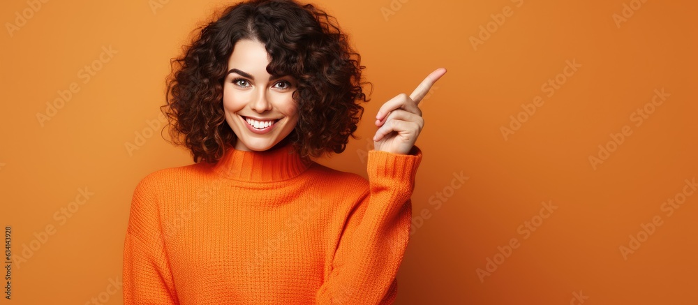 Obraz premium Young Caucasian brunette girl pointing to empty advertising space on orange background