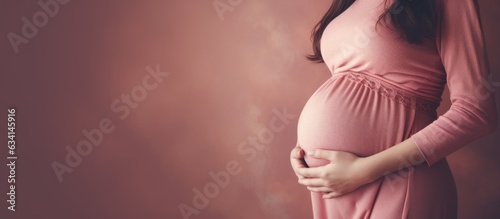 Pregnant woman with round belly wearing pink sweater