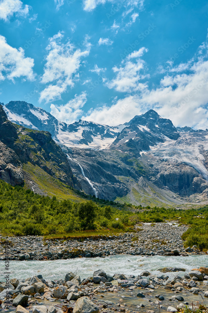 view of the glacier with a waterfall and a blooming meadow