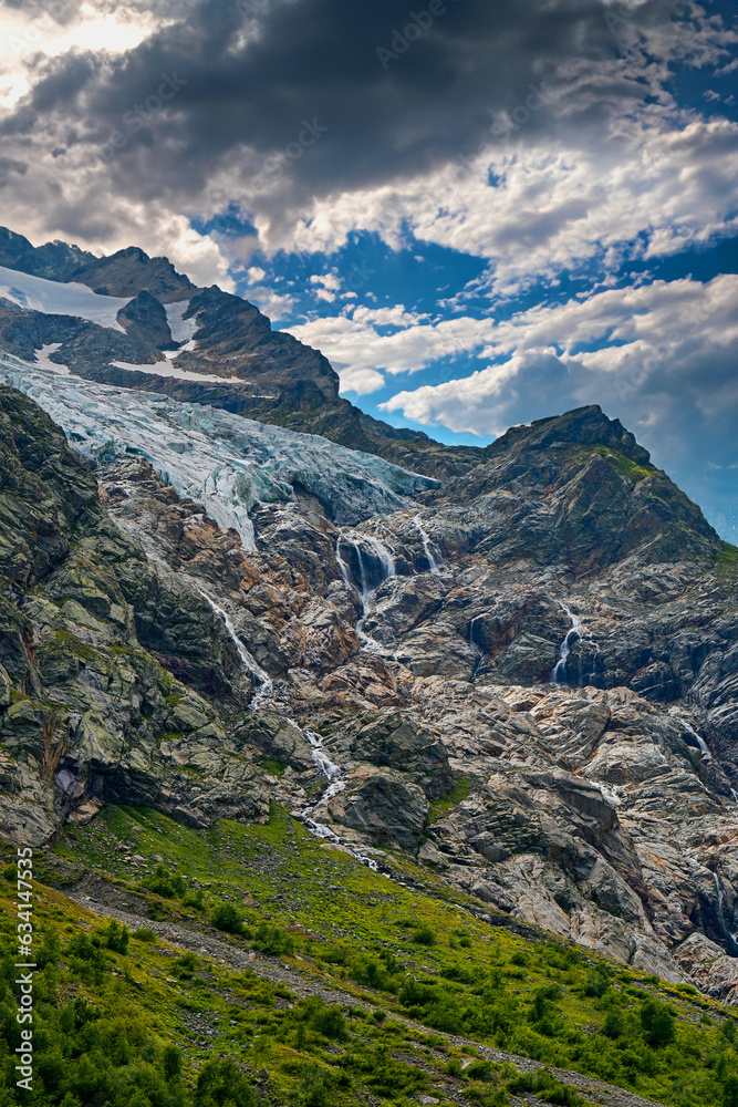 view of the glacier with a waterfall and a blooming meadow