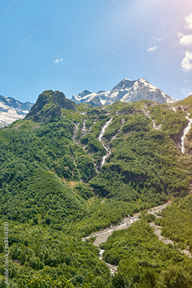 view of the glacier with a waterfall and a blooming meadow view of the glacier with a waterfall and a blooming meadow