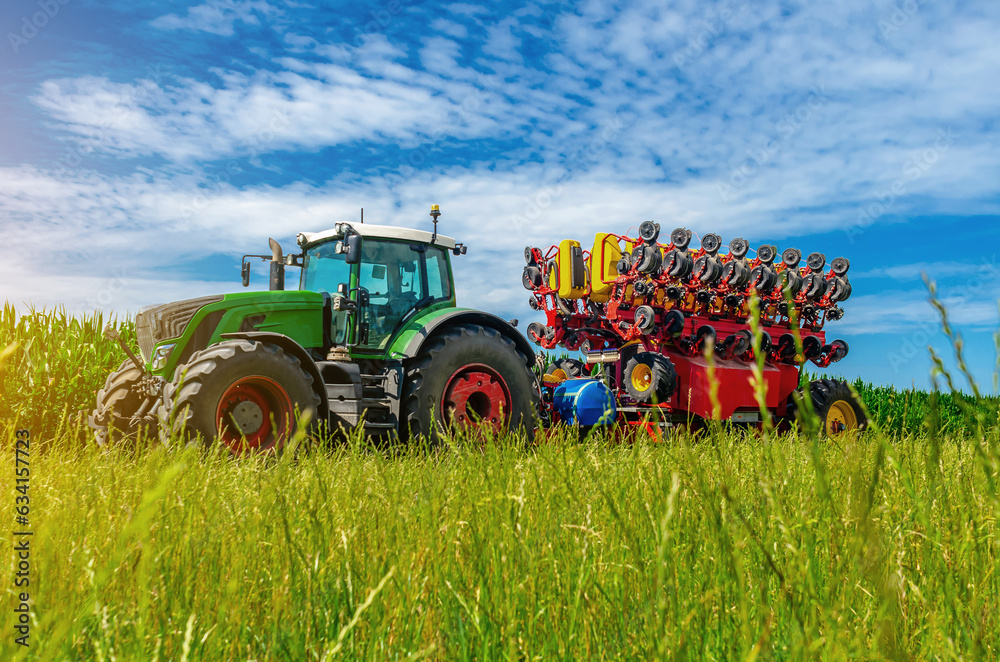 Large tractor on summer field. Low angle view through grass to tractor. Agricultural landscape Large tractor on summer field. Low angle view through grass to tractor. Agricultural landscape