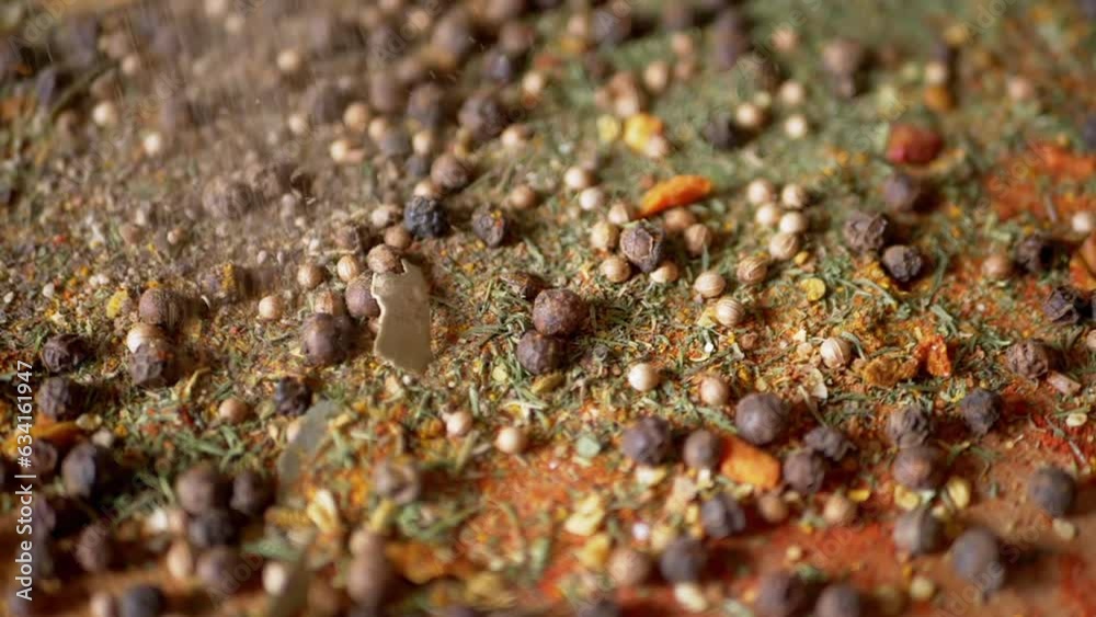 Dried Spices Falls on a Rotating Wooden Background of Colorful Spices. Close up. Slow motion. Scattered Indian spice mix, black peppercorns, turmeric, paprika, coriander, oregano. Background, texture. Dried Spices Falls on a Rotating Wooden Background of Colorful Spices. Close up. Slow motion. Scattered Indian spice mix, black peppercorns, turmeric, paprika, coriander, oregano. Background, texture.