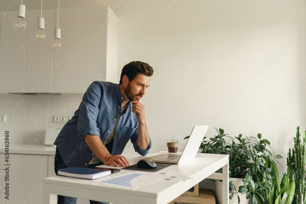 Male entrepreneur working on laptop on home kitchen. Distance work concept. High quality photo Male entrepreneur working on laptop on home kitchen. Distance work concept. High quality photo