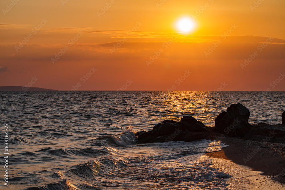 Sunset sun over the sea coast with stones