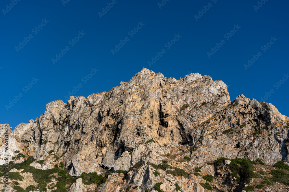 Close-up shot of Es Vedra Ibiza against a blue sky backdrop with sunlight
