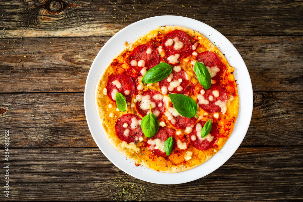 Upside down pizza with salami, mozzarella cheese and tomato sauce on wooden table Upside down pizza with salami, mozzarella cheese and tomato sauce on wooden table