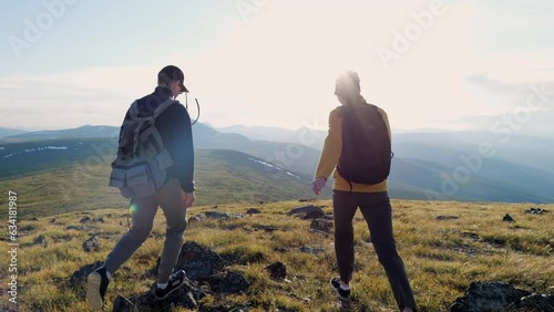 Hikers couple together raise arms and joy high achieve standing on mountain area back view. Travel success and hills valley walk of two happy young tourists