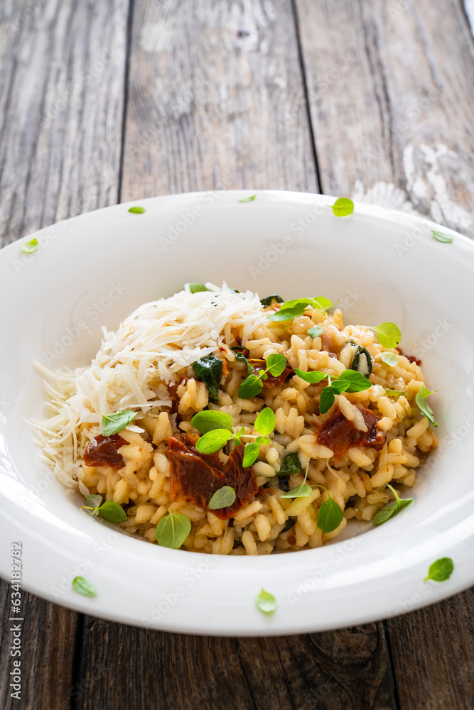 Risotto with sun dried tomatoes and Parmigiano Regiano  on wooden table
