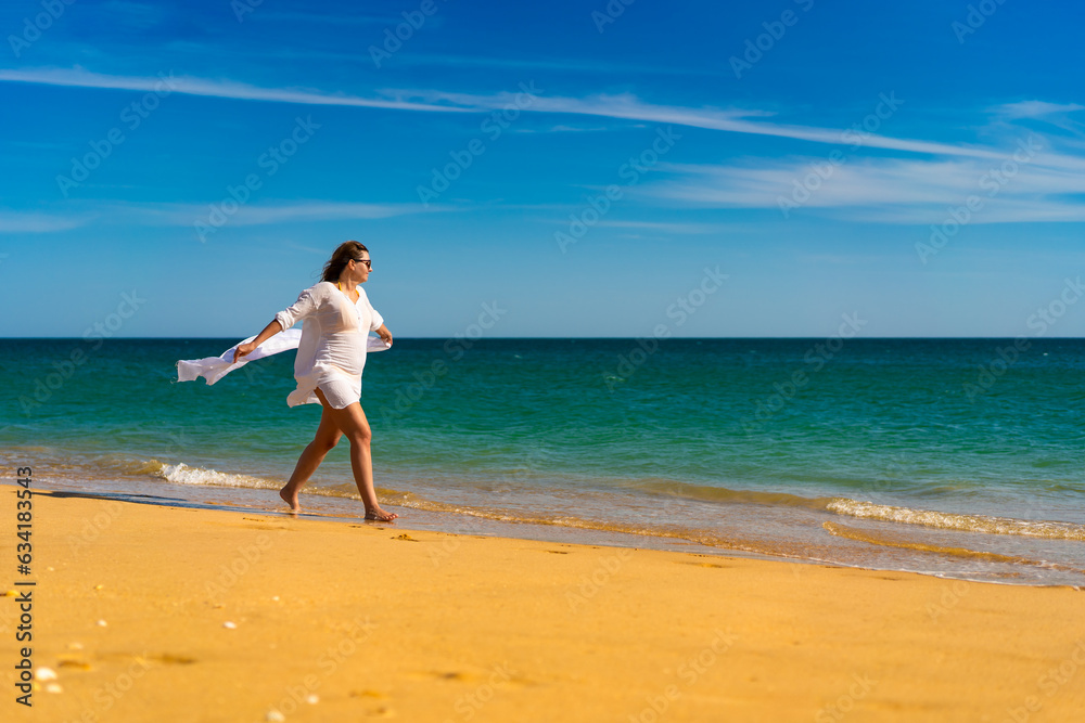 Beach holiday - beautiful woman walking on sunny beach holding shawl
Beach holiday - beautiful woman walking on sunny beach holding shawl