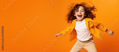 Cute Young Happy Girl iDancing on a Orange Background with Space for Copy
