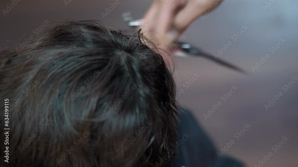 Hand Cutting Hair with Scissors and Comb in Close-up View.