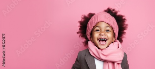 Cute Young African American Girl in Scarf and Hat for Winter on a Pink Background with Space for Copy