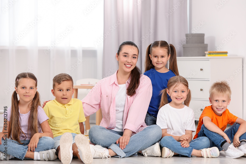 Happy nursery teacher and group of cute little children on floor in kindergarten. Playtime activities Happy nursery teacher and group of cute little children on floor in kindergarten. Playtime activities
