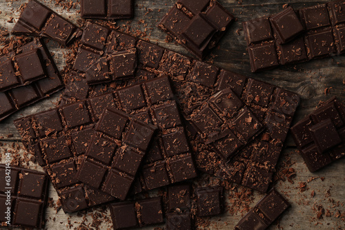 Pieces and shavings of tasty chocolate bars on wooden table, flat lay