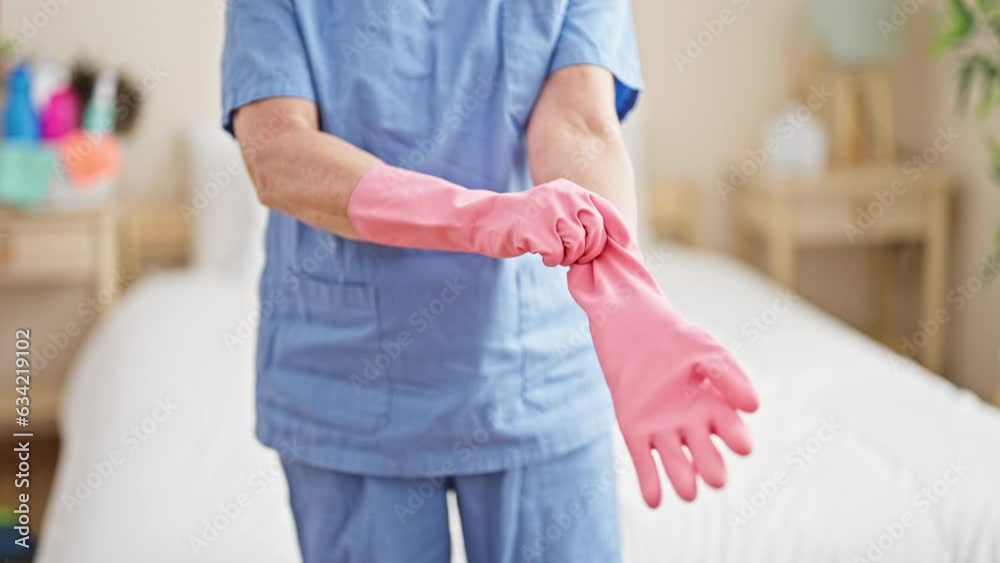 Middle age woman professional cleaner wearing gloves at bedroom Middle age woman professional cleaner wearing gloves at bedroom