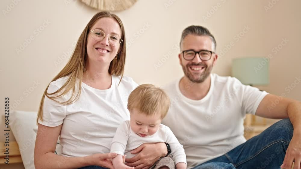 Family of mother, father and baby together sitting on the bed at bedroom Family of mother, father and baby together sitting on the bed at bedroom
