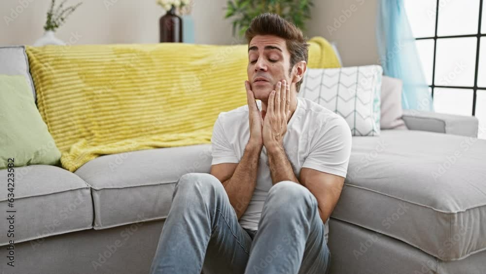 Young hispanic man stressed sitting on floor at home Young hispanic man stressed sitting on floor at home