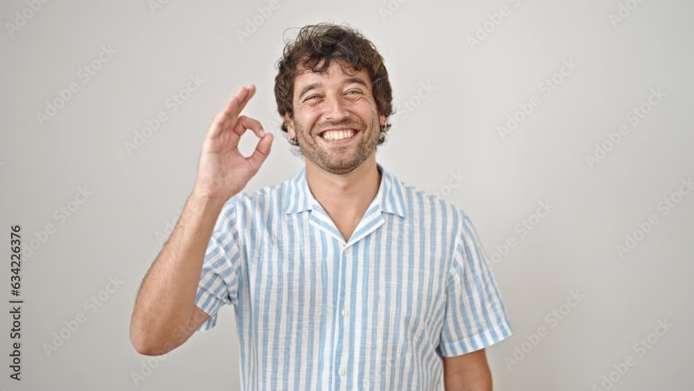 Young hispanic man smiling with ok gesture over isolated white background Young hispanic man smiling with ok gesture over isolated white background