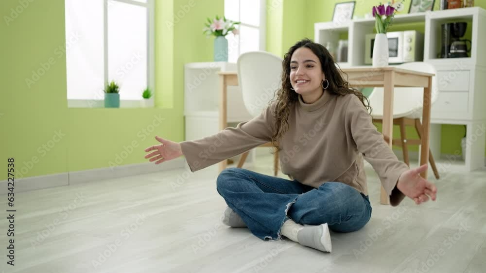 Young hispanic woman with dog sitting on floor hugging at dinning room Young hispanic woman with dog sitting on floor hugging at dinning room